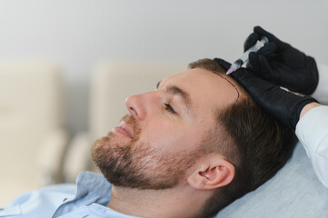 Man getting hair treatment at beauty salon, having mesotherapy session. Female therapist hands in...