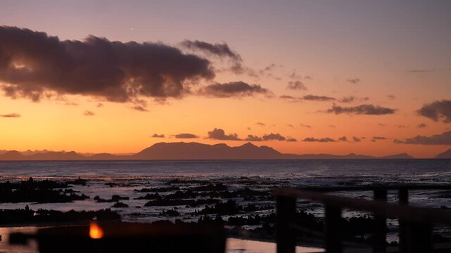 Sunset over False Bay near Pringle Bay village. A fire burns in a brazier, creating a warm glow against the stunning evening sky