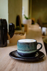 Coffee in blue cup on brown wooden table background top view. Morning in a cafe with a cup of cappuccino