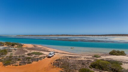 Scenic coastline with vehicle under clear blue sky