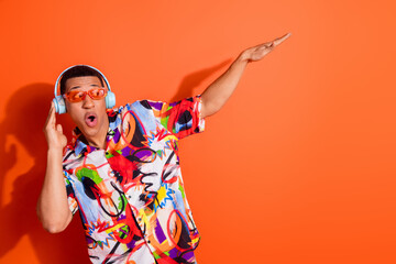 Energetic young man dancing to music in colorful headphones, sporting a vibrant patterned shirt...