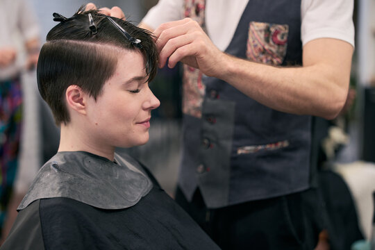 Hairdresser styling short hair of young female model in salon