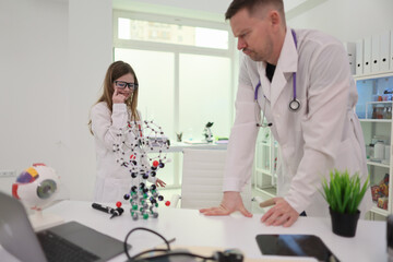 Fototapeta premium Two skilled healthcare experts are closely examining intricate molecular models within a modern laboratory environment