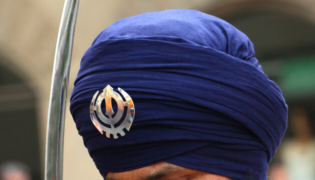 Sikh man wearing a blue Dastar with Khanda symbol and holding a Kirpan