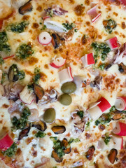Close-Up of Freshly Baked Seafood Pizza with Cheese, Olives, and Surimi