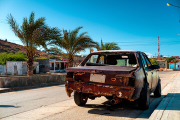 Photo of an old American car on Coche Island with colorful colonial houses and palms tree in the background, Venezuela.