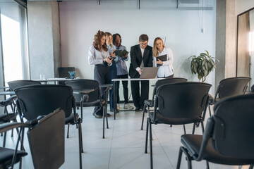 Standing by the laptop. Group of young business people are in conference room