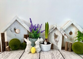 Easter decorative composition, home decoration for the holiday of bright Easter. On the table are cute rabbits and wooden houses, front view.