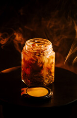 Warm jar of spiced beans rests on a table as steam rises in a cozy kitchen setting during evening hours