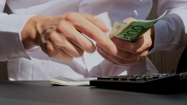 Expert trader hands showing Bitcoin coin digital gold after counting income banknotes of euro cash on calculator. Close up of hands unrecognizable Freelancer. Earned trading charts growth
