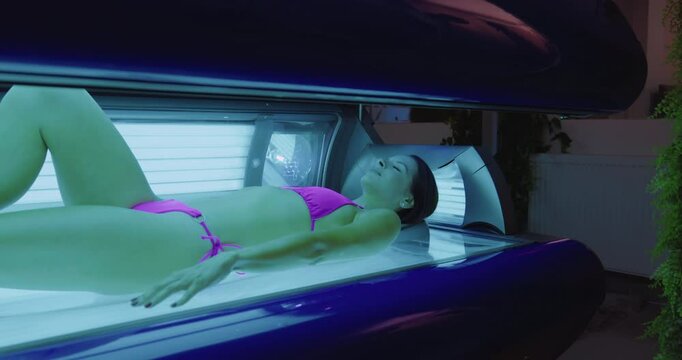 Young woman relaxing while tanning in solarium bed at spa salon