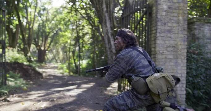 Spy beating up guard at dirt road gate then shooting others off screen with impressive skills - handheld shot