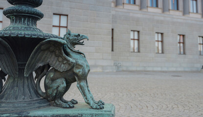 Naklejka premium Gryphon in front of Parliament in Vienna, Austria. Majestic Austrian Parliament Building, an iconic symbol of democracy, captured in warm sunlight against vibrant cityscape.