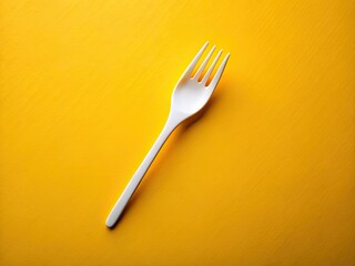 Vibrant yellow background highlights a pristine white plastic fork; ideal for disposable tableware promotion.