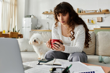 Young woman enjoys a cozy afternoon sipping tea while studying at home with her dog nearby