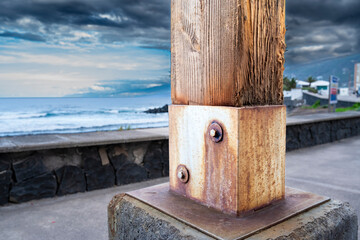 A rusty metal pole is leaning against a stone wall. The pole is located near the ocean and has a weathered appearance. Concept of nostalgia and the passage of time