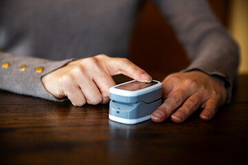 an adult woman measures her oxygen level on her finger