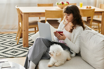Young woman enjoying a cozy morning with her pet while working on a laptop at home