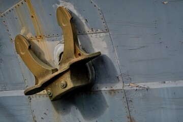 View of a ship's anchor on an anchor hole. Wooden hull of a ship. Close-up