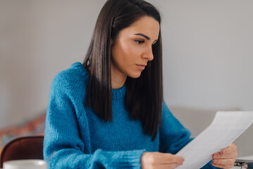 Focused businesswoman reading document at home office desk