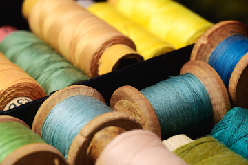 Lot of colored spools different sizes with thread in box