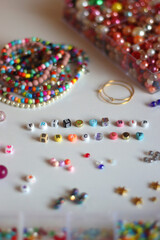 Friendship bracelet spelled with letter beads. Colorful handmade bracelets and various jewelry making supplies. Selective focus, white background.
