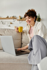 Young woman enjoys her morning coffee while working on her laptop at home in a cozy setting