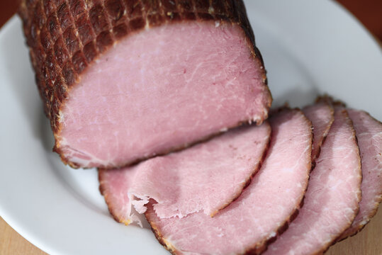 Schab wędzony, wędlina krojona na plasterki na talerzu z bliska