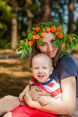 Young mother and her one-year-old baby taking pictures in autumn park bushes