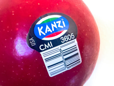 Calgary, Alberta, Canada. Mar 1, 2025. A close-up of a Kanzi apple with a sticker displaying the brand and a PLU code. The apple is red and shows some texture.