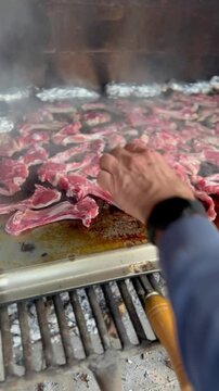 Lamb chops cooking on a smoking grill. Outdoor barbecue. Vertical video.