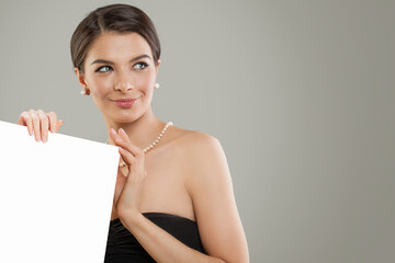 Happy woman with open hand and white empty board background with copy space for advertising...