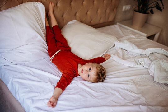 cute little naughty baby lying on parents bed, doesn't want to sleep. baby daytime sleep, how to put kids to bed, bedtime rituals, blond boy with blue eyes
