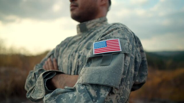 Us Army veteran honors Veterans Day. Man soldier adjusts the US military patch before duty. A US soldier with an American flag patch on his uniform prayers for Memorial Day. Independence Day.
