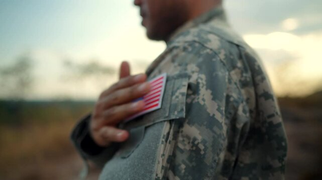 Us Army veteran honors Veterans Day. Man soldier adjusts the US military patch before duty. A US soldier with an American flag patch on his uniform prayers for Memorial Day. Independence Day.
