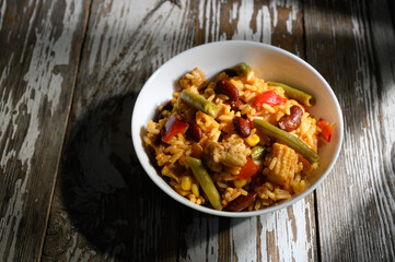 Vibrant rice bowl filled with vegetables and chicken in a cozy rustic setting