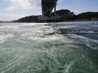 It says "Naruto" in Japanese. In the Naruto Strait, Tokushima Prefecture, Japan, the ocean creates swirling waves due to special tidal currents.