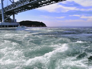 It says "Naruto" in Japanese. In the Naruto Strait, Tokushima Prefecture, Japan, the ocean creates swirling waves due to special tidal currents.