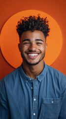 Fototapeta premium Man smiles in denim shirt, studio setting, orange circle background, for portrait use