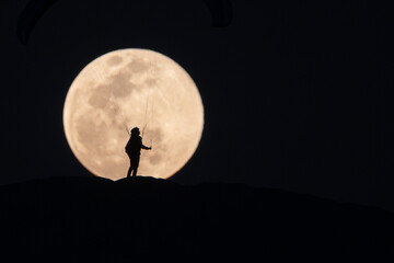 Sylwetka paralotniarza na tle pełni księżyca – nocna fotografia  © lojak