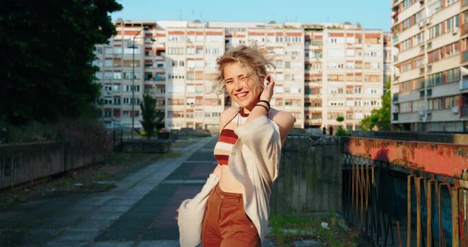 Carefree young woman laughing out loud in a run-down urban environment, expressing joy and freedom