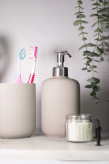 Hygiene items like toothbrushes and liquid hand soap on a marble tray, complemented by greenery in a light, airy interior.