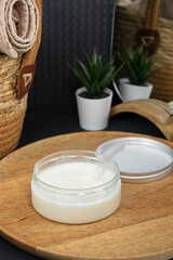 A straw basket with towels and a wooden tray holding cream or coconut oil, showcasing natural tones, perfect for face and body care, skincare, and spa treatments with natural oils.