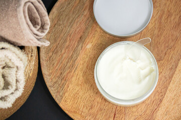 A jar of cream on a wooden tray, emphasizing natural ingredients, skincare, spa, and relaxation.