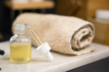 A serum bottle on a marble tray with a soft towel, set against a black background and wooden elements,  face care, hydration, nourishment, and spa treatments, promoting skin health and beauty.