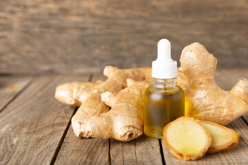 Ginger essential oil on texture background. Fresh ginger slices. Essence, serum, oil. Alternative...
