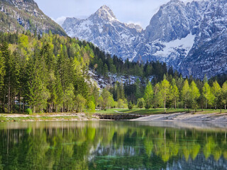 Emerald waters of jasna lake reflecting snow-peaked julian alps, creating serene springtime landscape within triglav national park, slovenia
