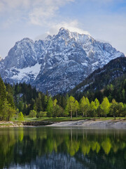 Julian alps casting perfect reflection on glassy jasna lake waters, showcasing serene mountain landscape in triglav national park, slovenia