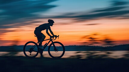 Fototapeta premium A silhouette of a cyclist on a gravel bike at dusk, with motion blur enhancing the scene.