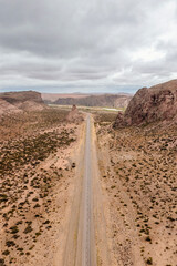Aerial view of rural road with desert landscape with big cliffs made of sandstone. Los Altares, Chubut province, Argentina
